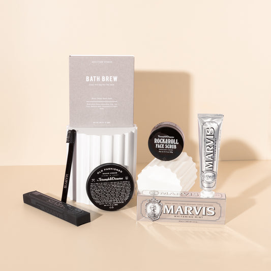 Style Photography of pamper gifts for him filled with men's self care products such as shaving cream , face scrub , toothpaste and bath soak